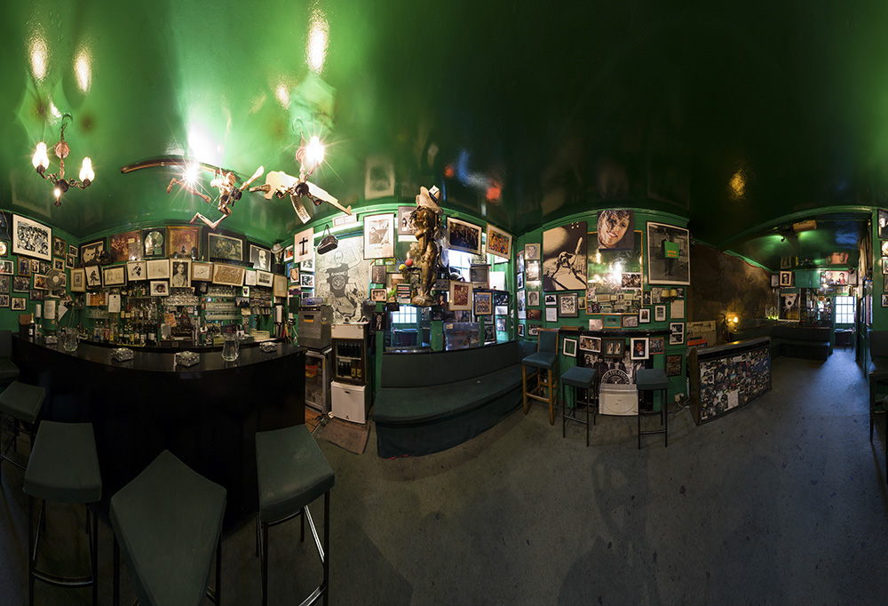 Stitched panoramic photograph of the green interior of the Colony Room Club, filled with framed artworks and photographs